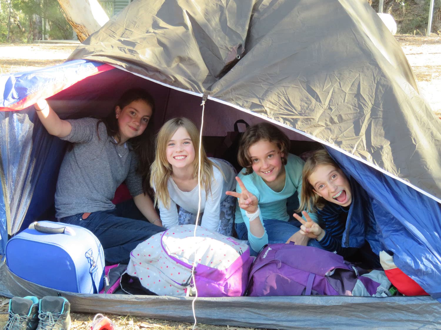 Four students share smiles and camaraderie inside a tent during a Kindlehill school camp in the Megalong Valley.