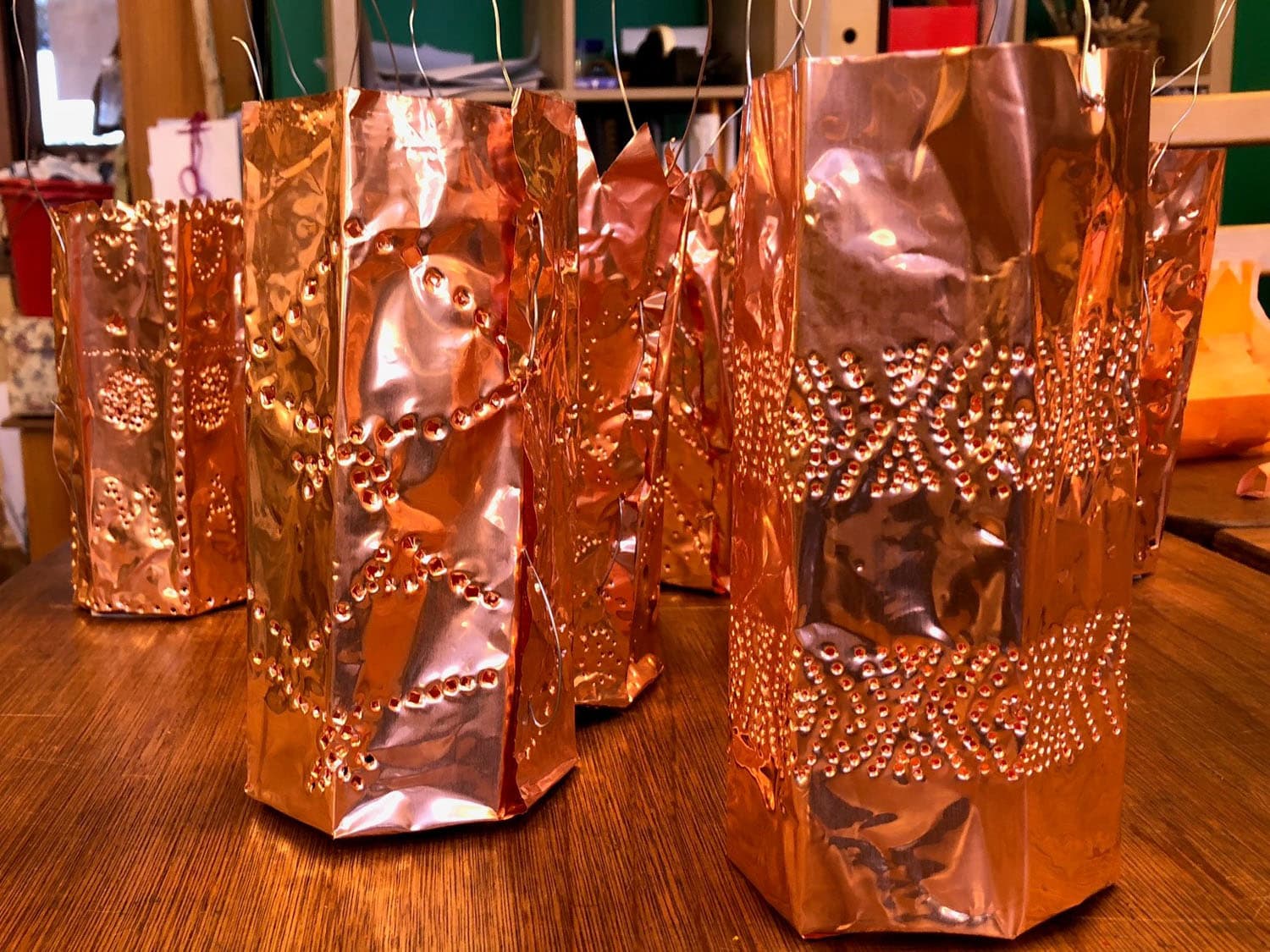 Hand-punched copper lanterns prepared for the winter walk, honouring seasonal rhythms and the shared warmth of community.