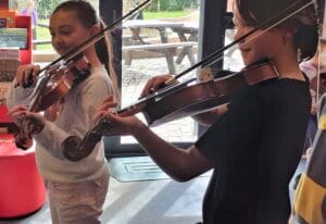 Students focus intently while playing violins, embodying heart-centred musical growth and shared rhythmic expression at Kindlehill.