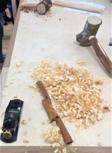 Traditional tools and timber shavings showcase students physical labour, crafting mallets and stools from raw, local green wood.