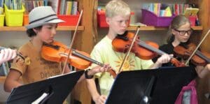 Focused students perform a string ensemble at Kindlehill, demonstrating artistic expression through creative cooperation and shared purpose.
