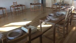 Natural cane coils rest on timber tables in a sunlit studio for a purposeful basket weaving workshop.