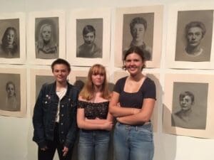 Kindlehill students stand with their charcoal portraits, demonstrating technical mastery and individual growth within a supportive creative community.