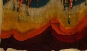 Layered textile ridges in ochre tones under beaded stars, representing Kindlehills connection to Country and enduring community wisdom.