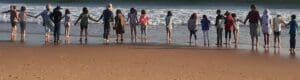Kindlehill students stand hand-in-hand along the shoreline, fostering community spirit and a deep connection to Country.