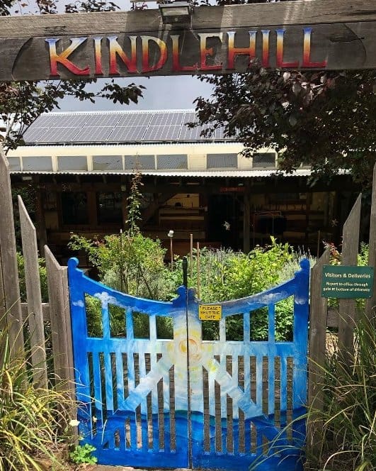 Vibrant gates open to a sustainable garden sanctuary, welcoming families into Kindlehills creative, nature-centred village school.