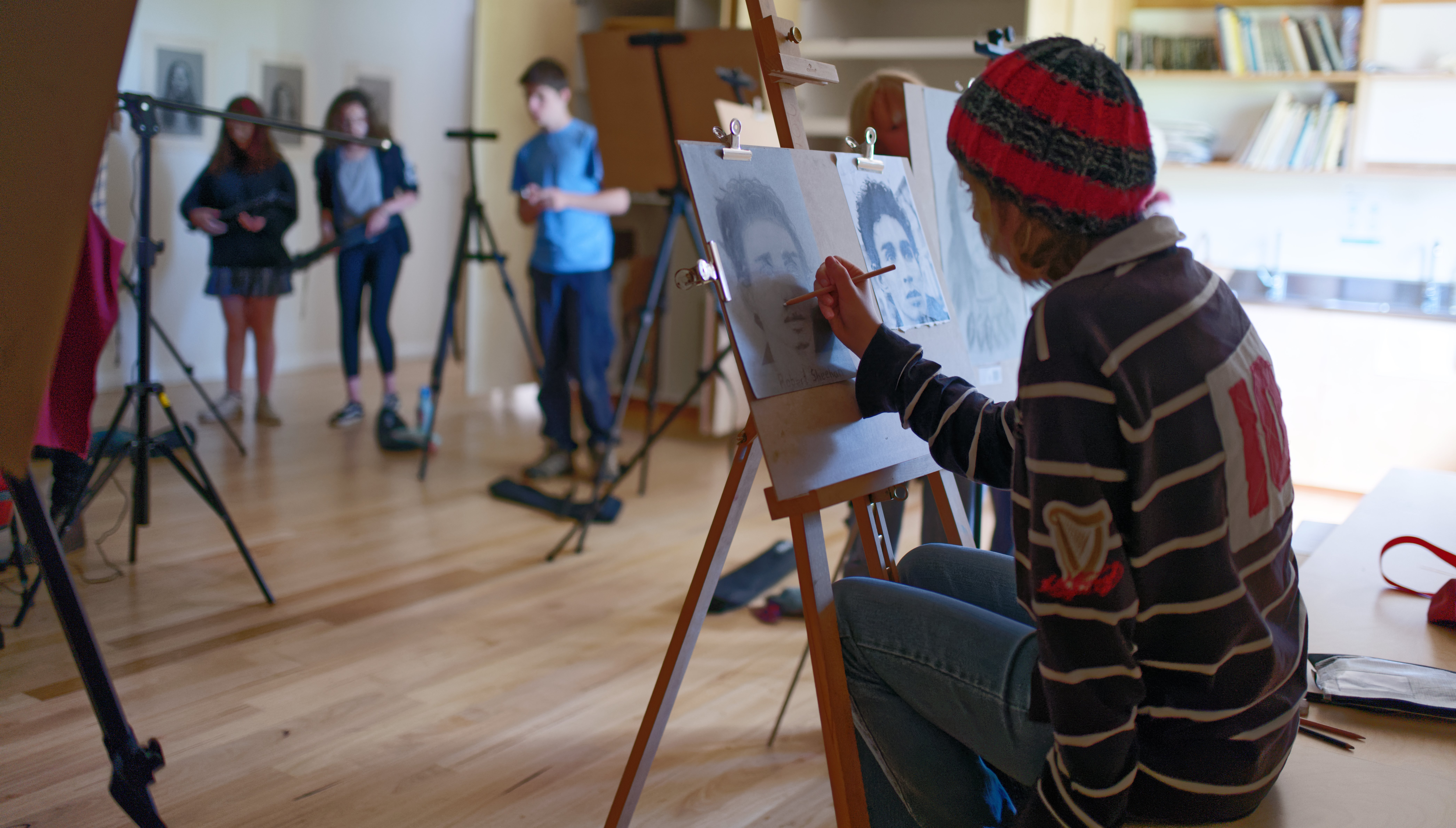 A student sketches a portrait, awakening imagination through artistic expression with head, heart, and hands.
