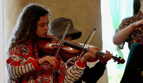 Students play violins, uniting head, heart, and hands through collaborative musical expression within the Kindlehill school community.