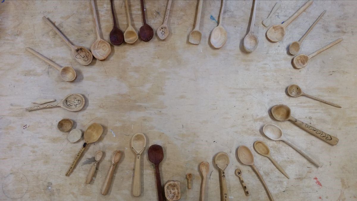 Hand-carved wooden spoons lie in a circle, honouring unique developmental journeys and a shared, artistic connection to nature.