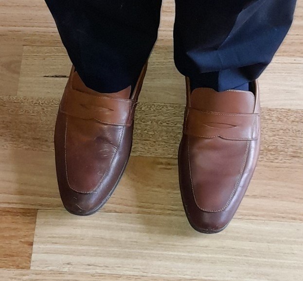 Grounded leather shoes on timber flooring symbolise walking an individual path to re-story and restore our world.