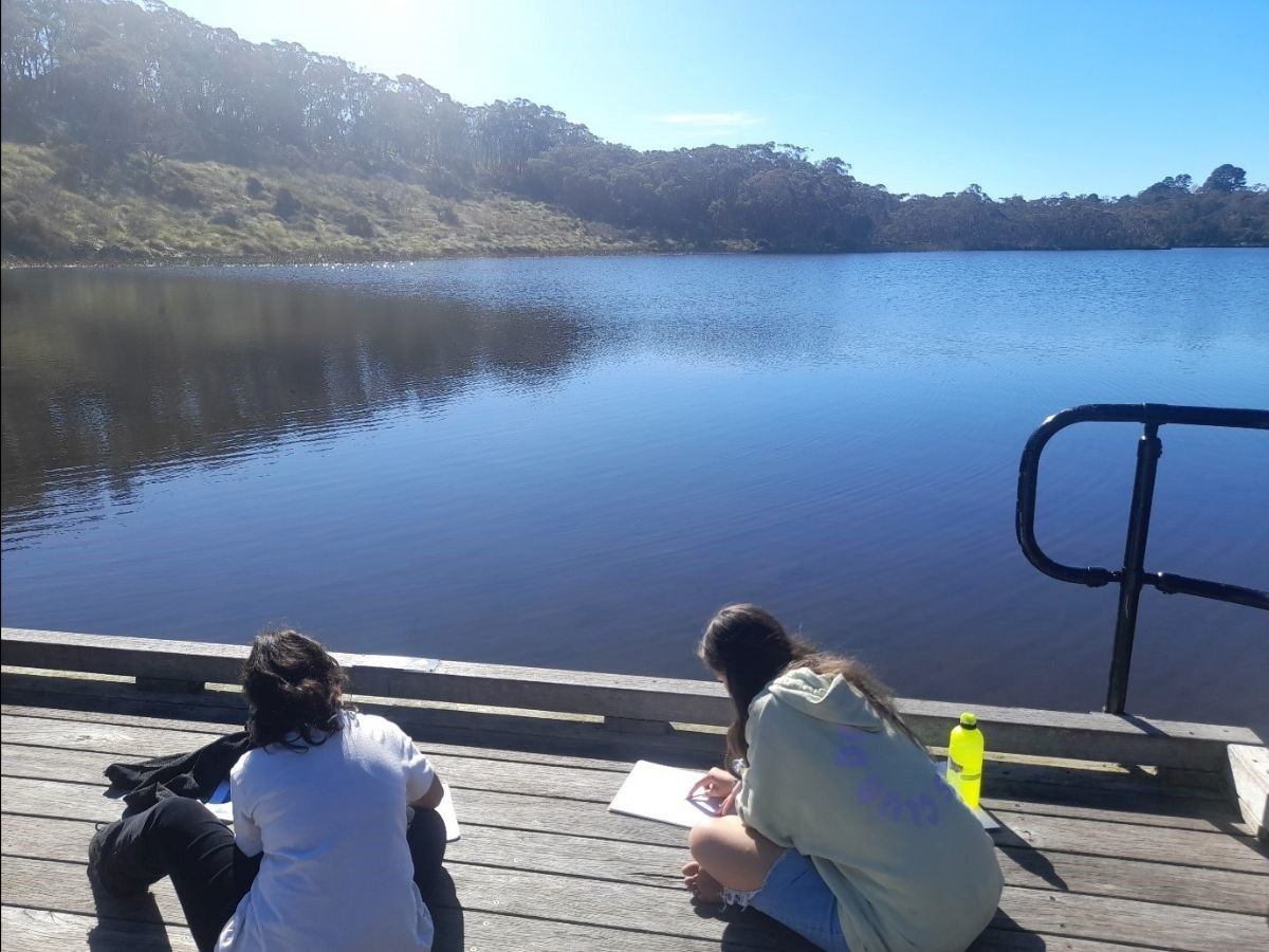 Students sit on a sunny jetty at Wentworth Falls Lake, documenting the environment and connecting deeply with Country.