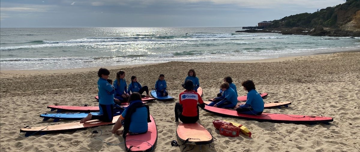 Kindlehill students gather in a surfboard circle, connecting to Country and each other through stories by the ocean.