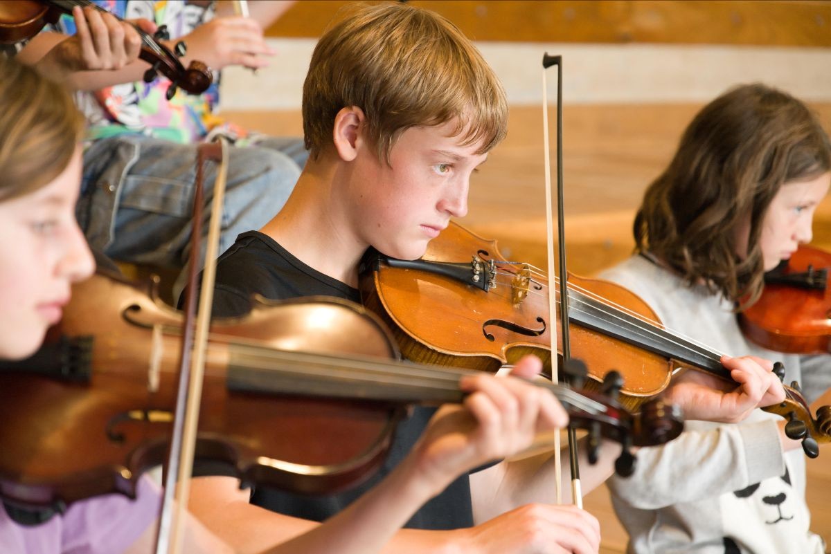 Focused students express head, heart, and hands through collaborative musical performance within the string ensemble.