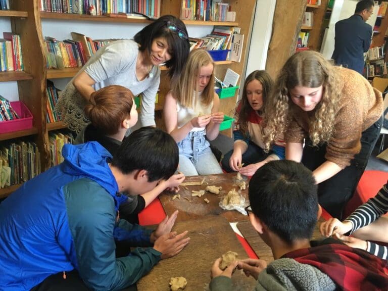 Kindlehill students and a teacher collaborate on clay moulding, fostering a shared sense of community and artistic expression.