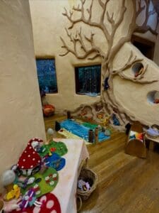 Earthen walls and a sculpted tree create a magical Kindlehill playgroup space for nature-based storytelling and imaginative play.