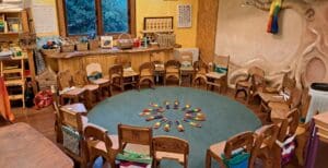 Wooden chairs form a welcoming circle, honouring community connection and the rhythmic heart of the Kindlehill classroom village.