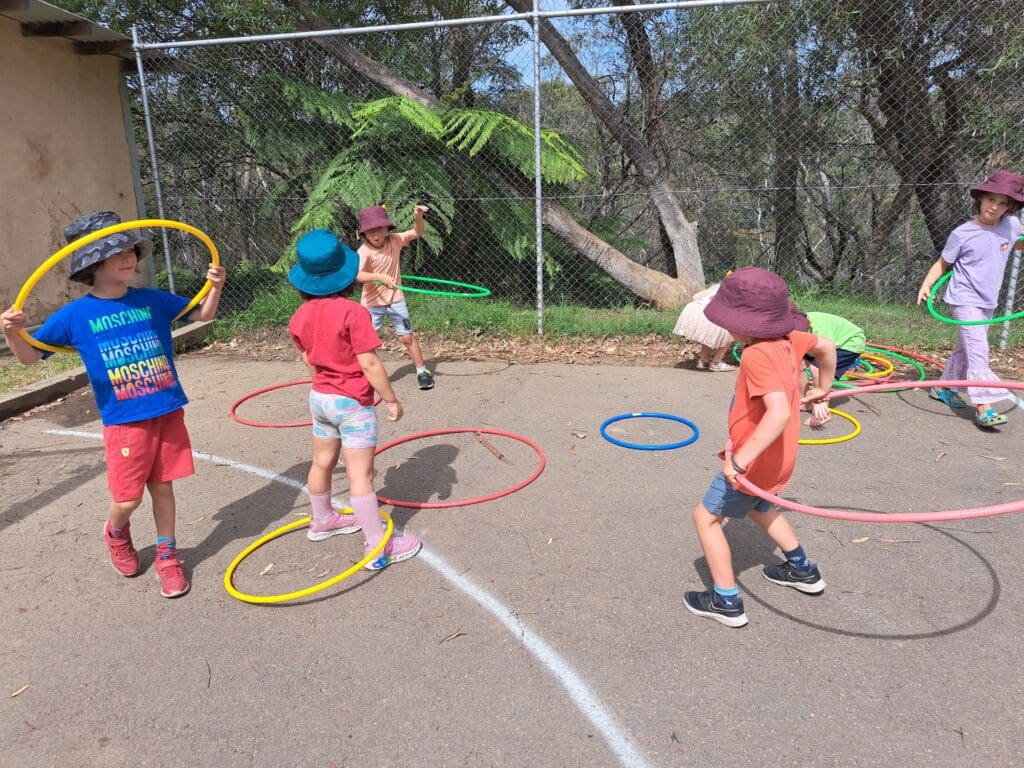 Children cultivate physical rhythm and social connection through colourful hula hoop play amidst the native Blue Mountains bushland.