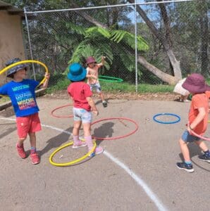 Children cultivate physical rhythm and social connection through colourful hula hoop play amidst the native Blue Mountains bushland.