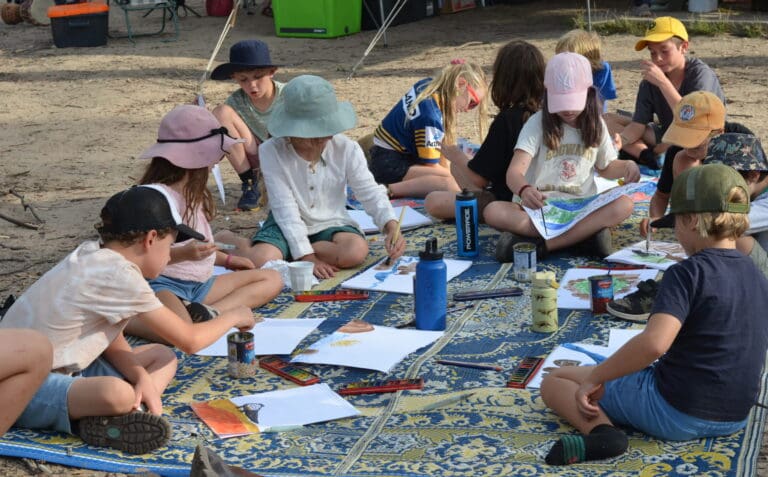 Kindlehill students cultivate creativity and connection by painting watercolours together during a shared bushland camping experience.