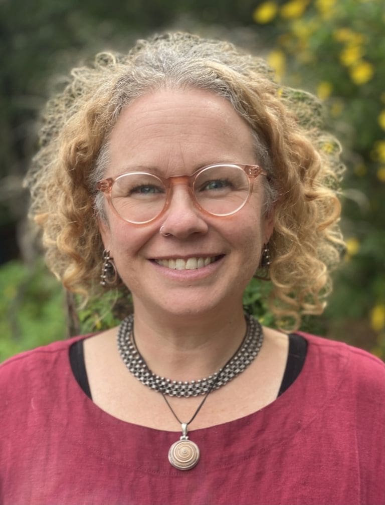 A smiling educator embodying Kindlehills warm community spirit and a deep, nurturing connection to the living world.