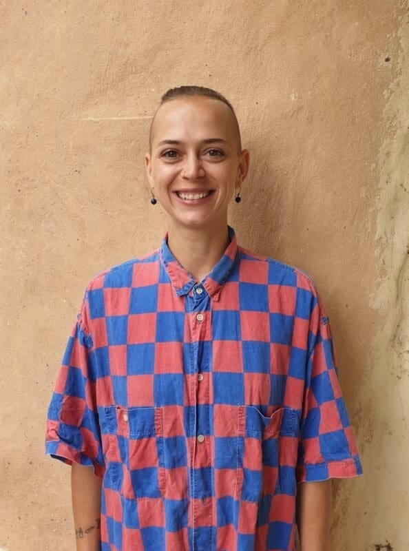 Smiling Kindlehill educator radiating warmth and authenticity, embodying the courage to walk an individual path against an earthy backdrop.