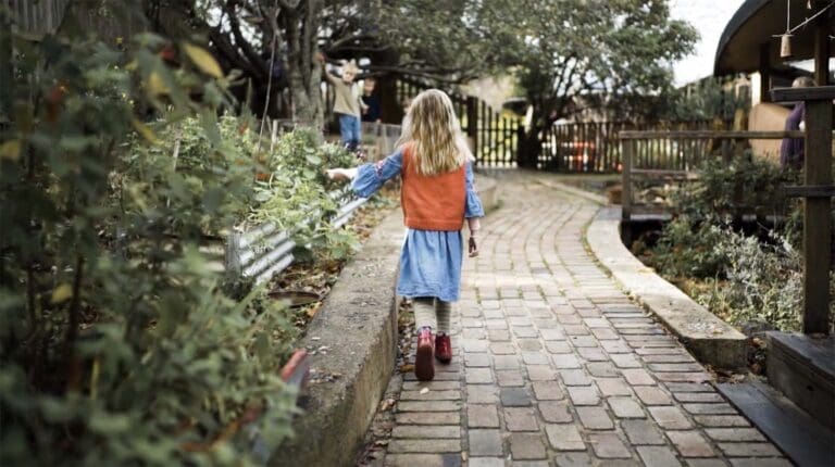 Children wander through lush garden paths, honouring the rhythmic beauty of nature through discovery and wonder.