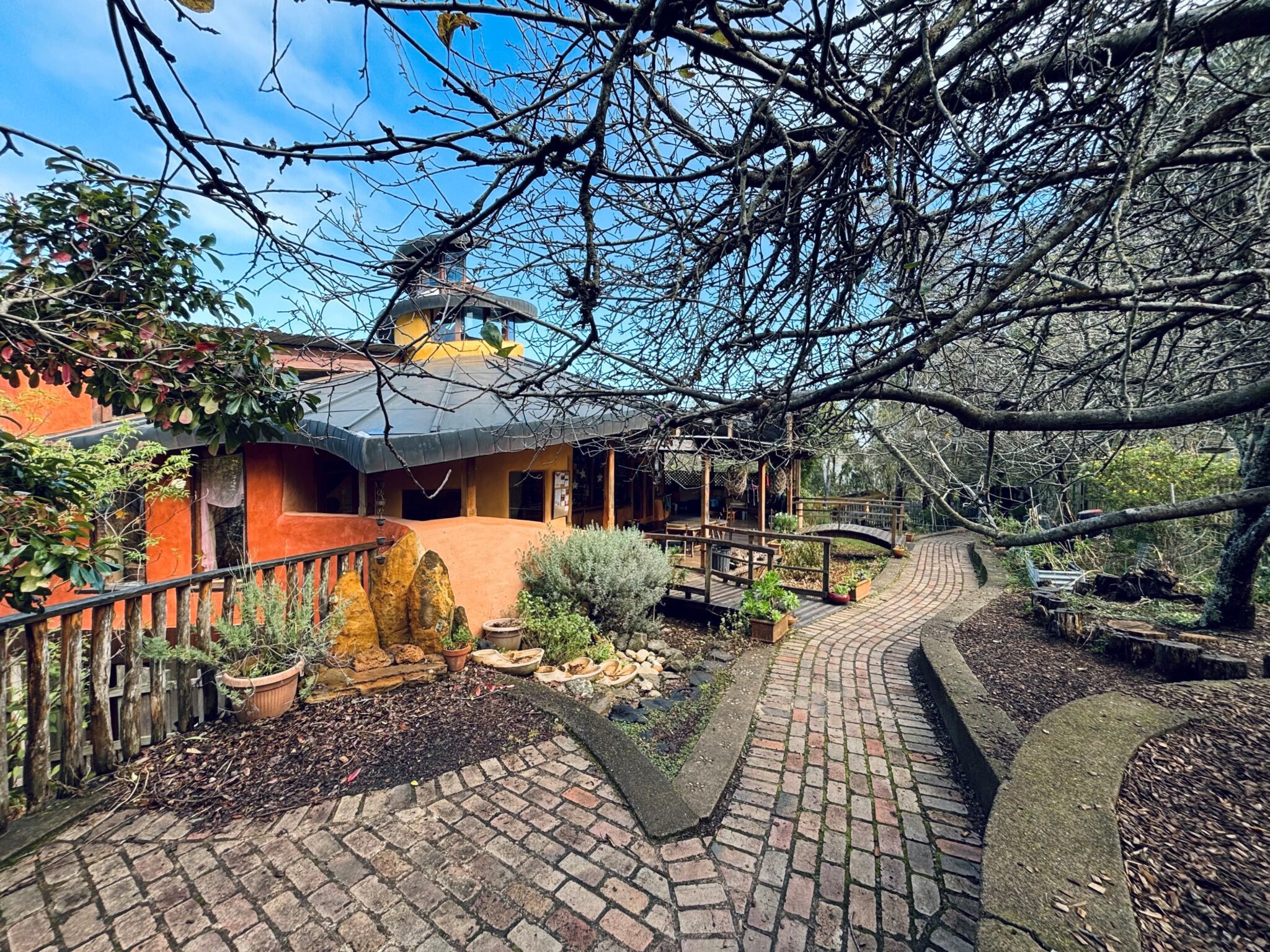 Curved brick paths through native bushland connect Kindlehills earth-coloured classrooms to the seasonal rhythms of Country.